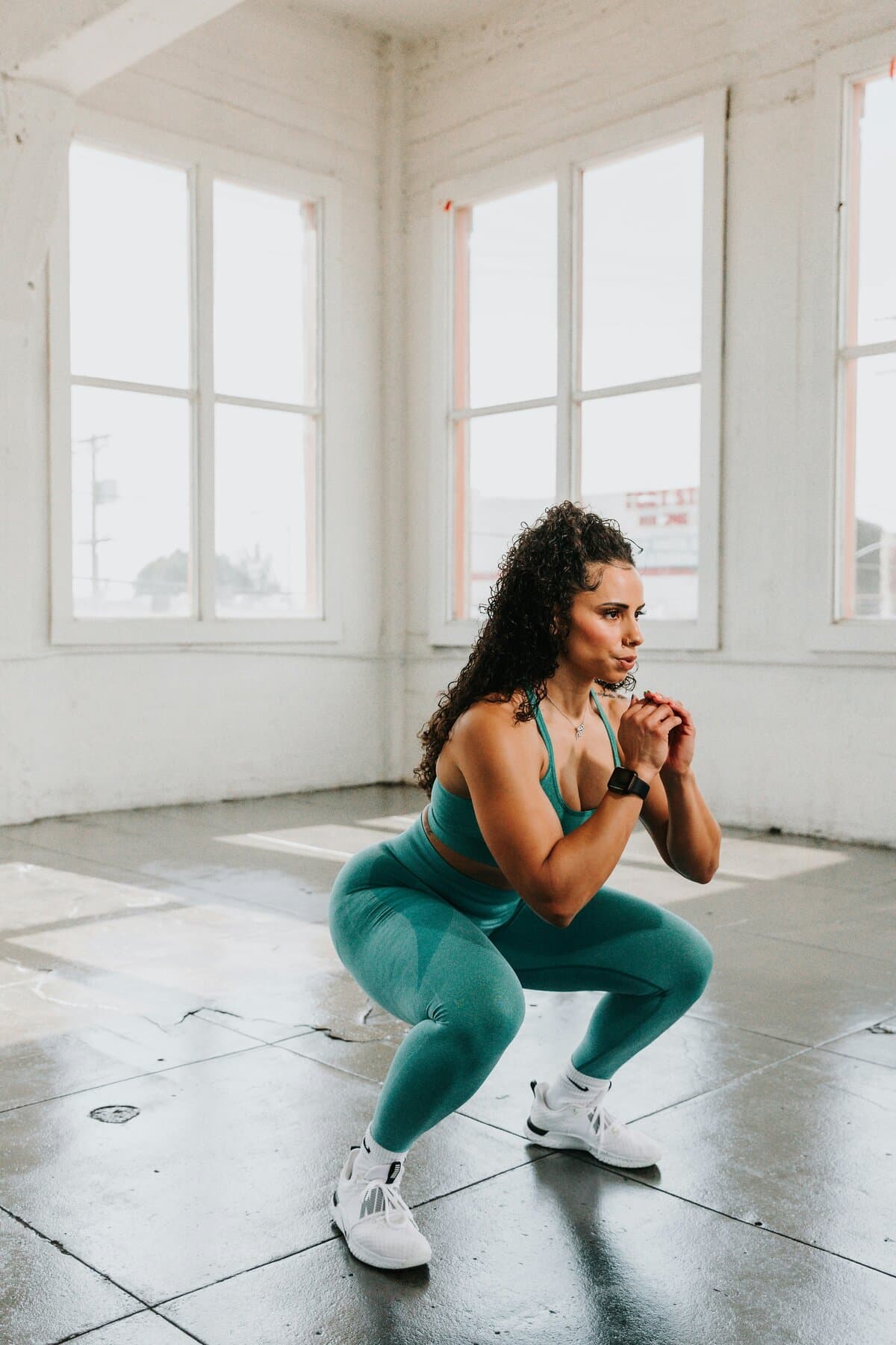 Athlete holding a deep squat in a bright sunlit studio